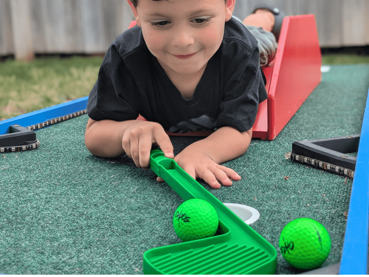 A child playing mini golf and hitting the ball into the hole.