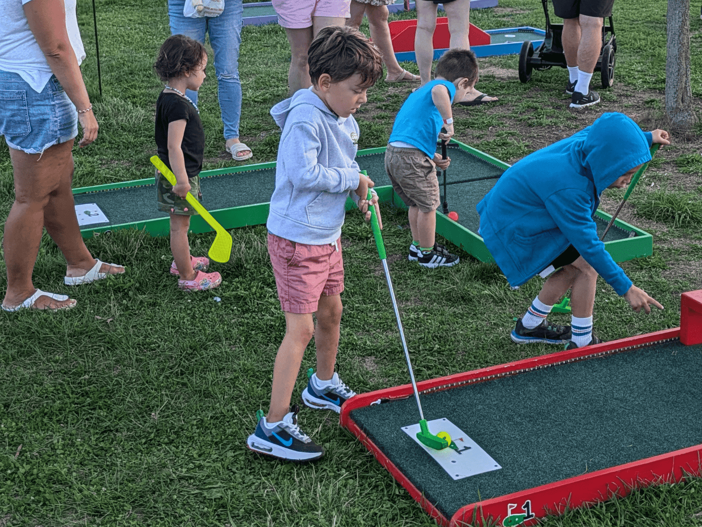 a kid playing mini golf and hitting the ball into the hole.