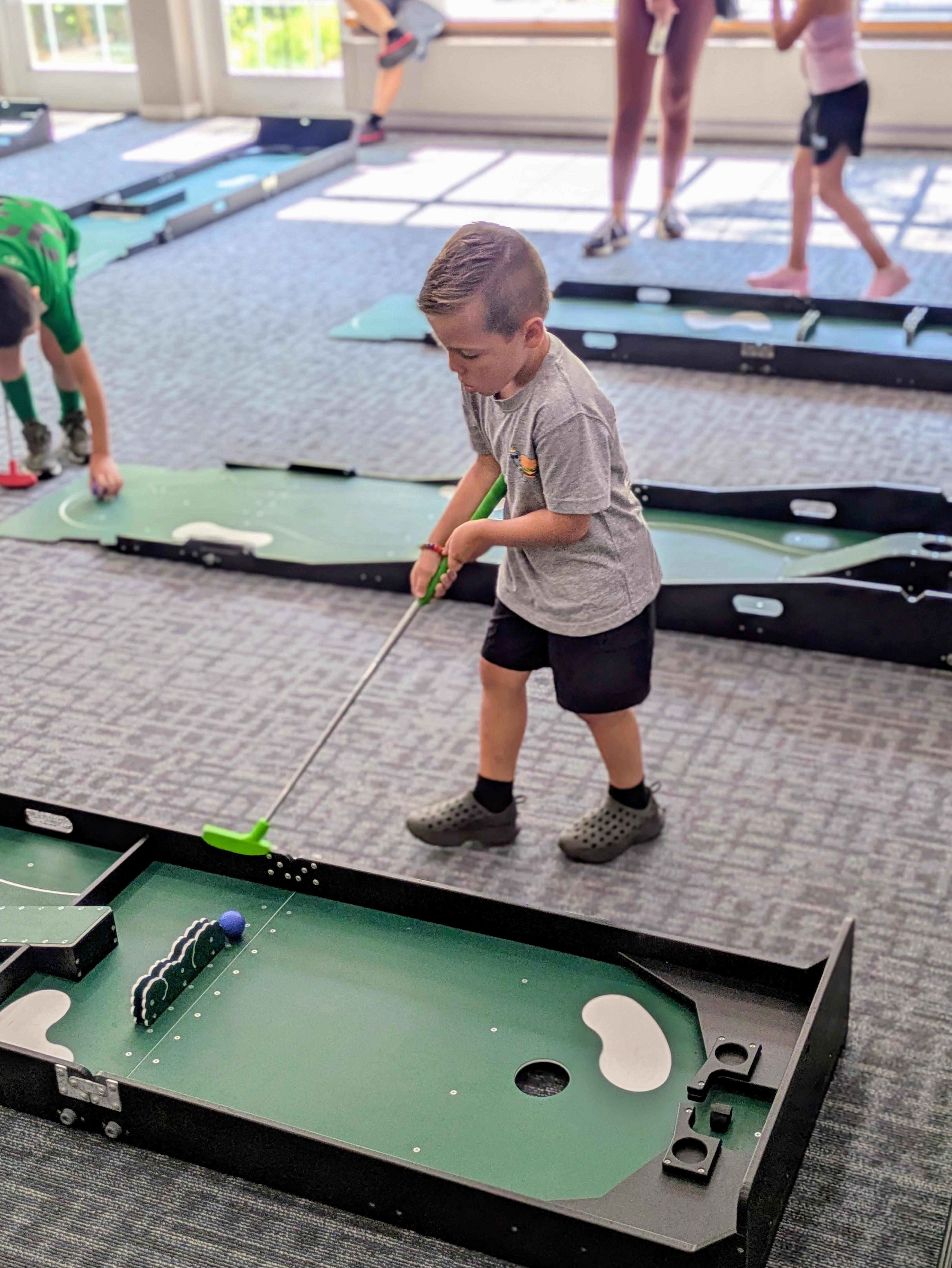 a child playing mobile mini golf inside of a building.